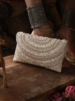 Elegant beaded clutch bag on a wooden surface with decorative arm bands.