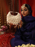 Woman in traditional attire holding a pearl-handled bag against a decorative background