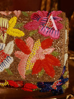 Decorative clutch with floral patterns and a letter 'A' on a dark background