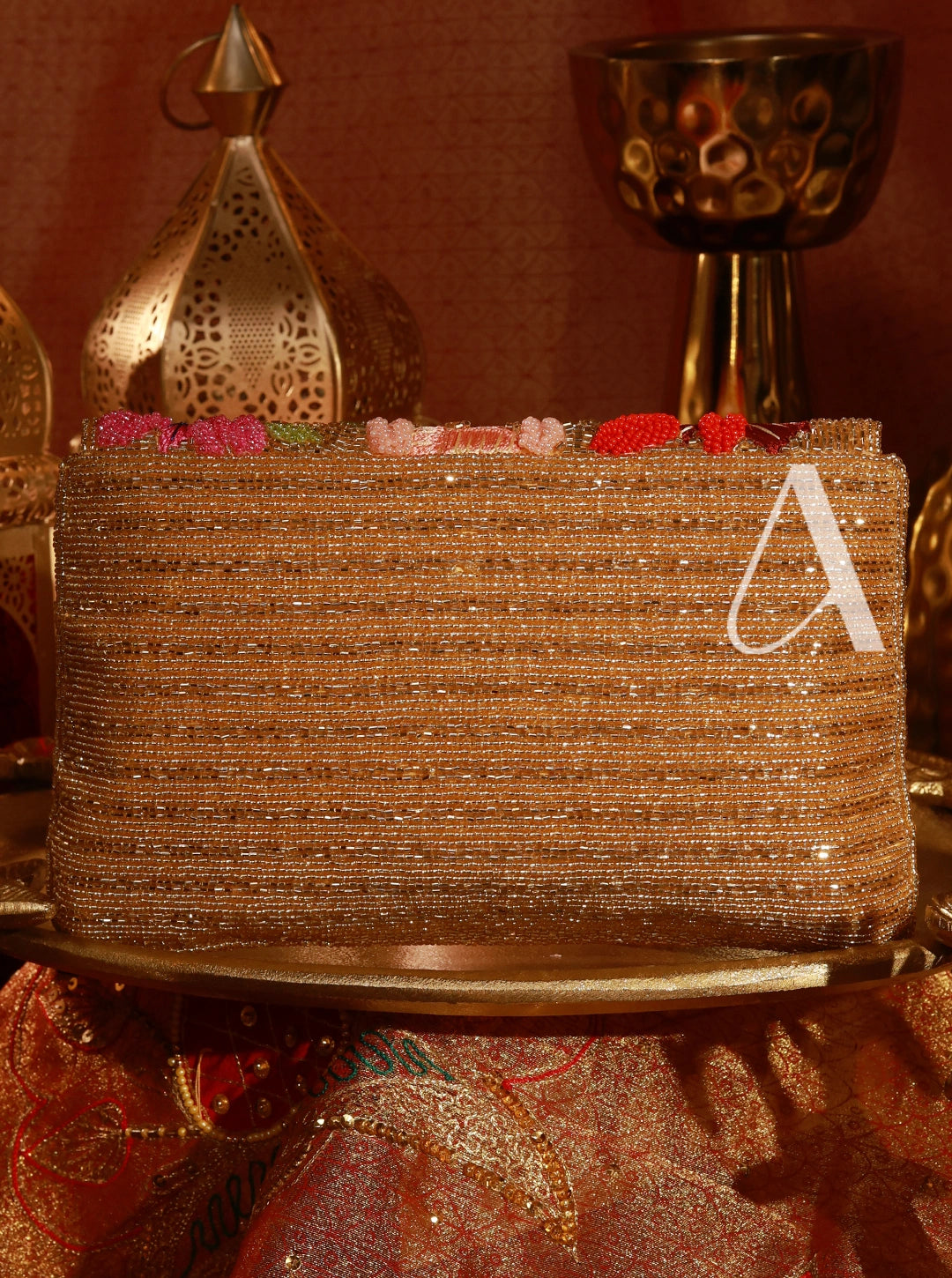 Decorative cake with gold glitter and a letter 'A' on a patterned surface.