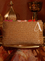 Decorative cake with gold glitter and a letter 'A' on a patterned surface.