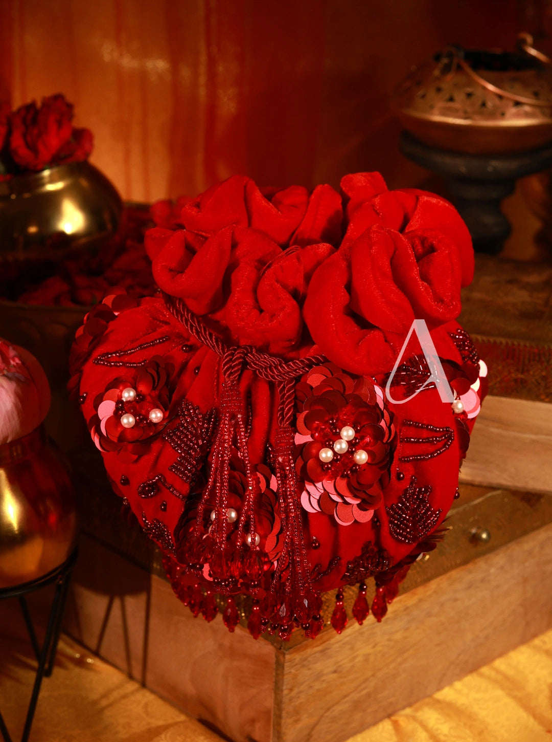 Red decorative item with beads and tassels on a wooden surface