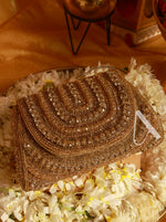 Gold beaded clutch on a floral surface with a blurred background