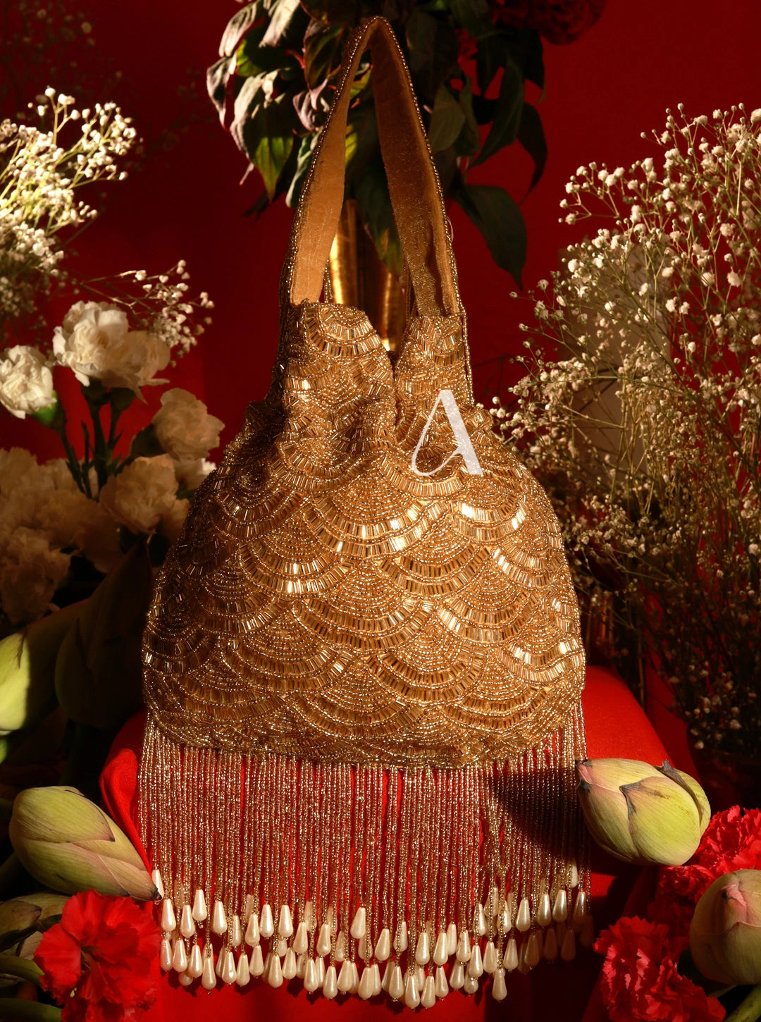 Gold beaded handbag with fringe on a red background with flowers