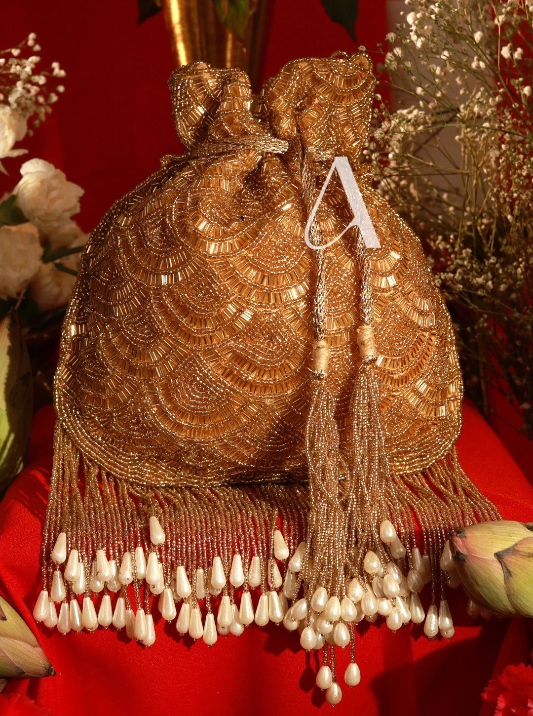 Gold beaded handbag with tassels on a red background