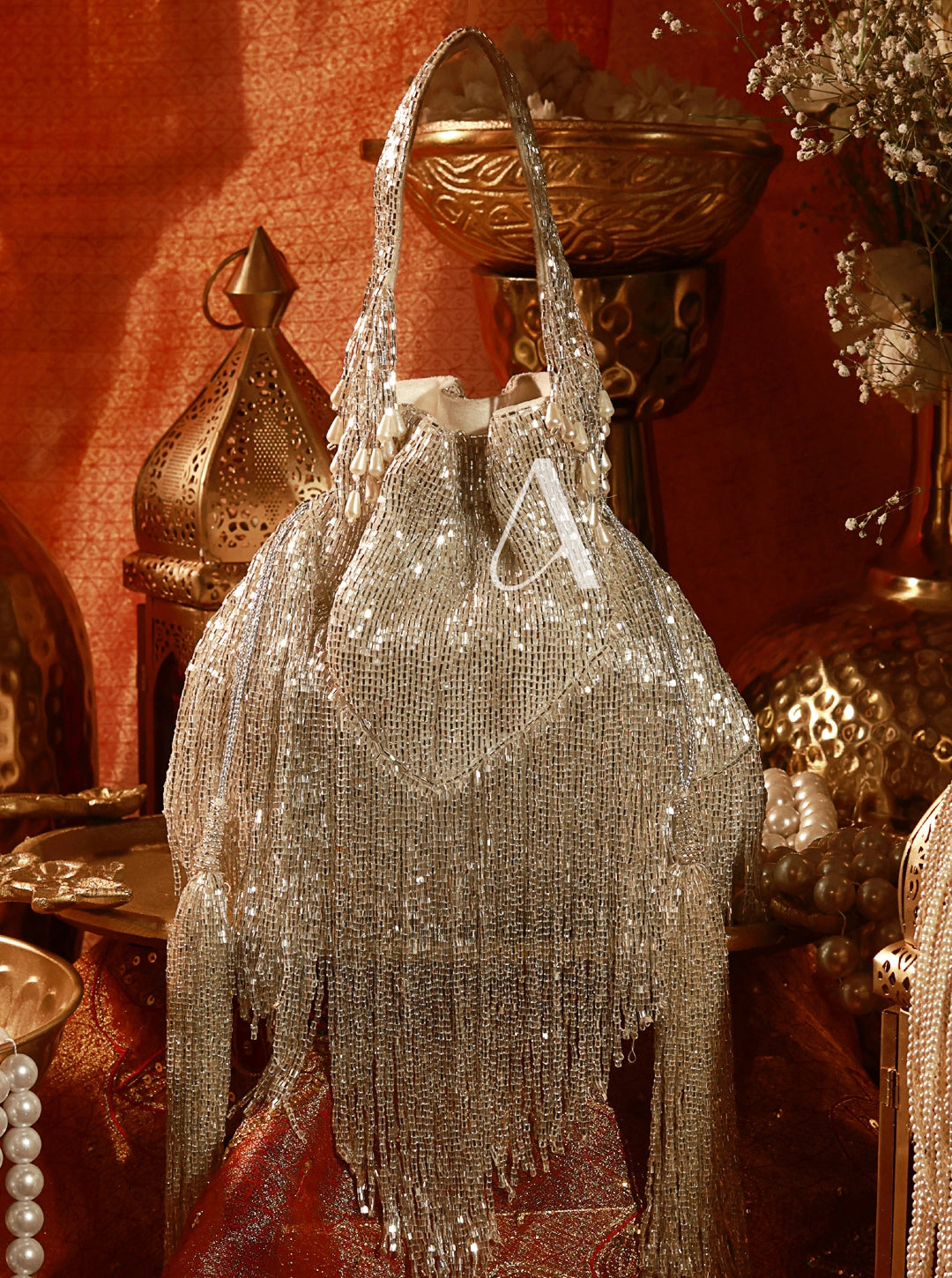 Silver beaded handbag with fringe on a decorative background