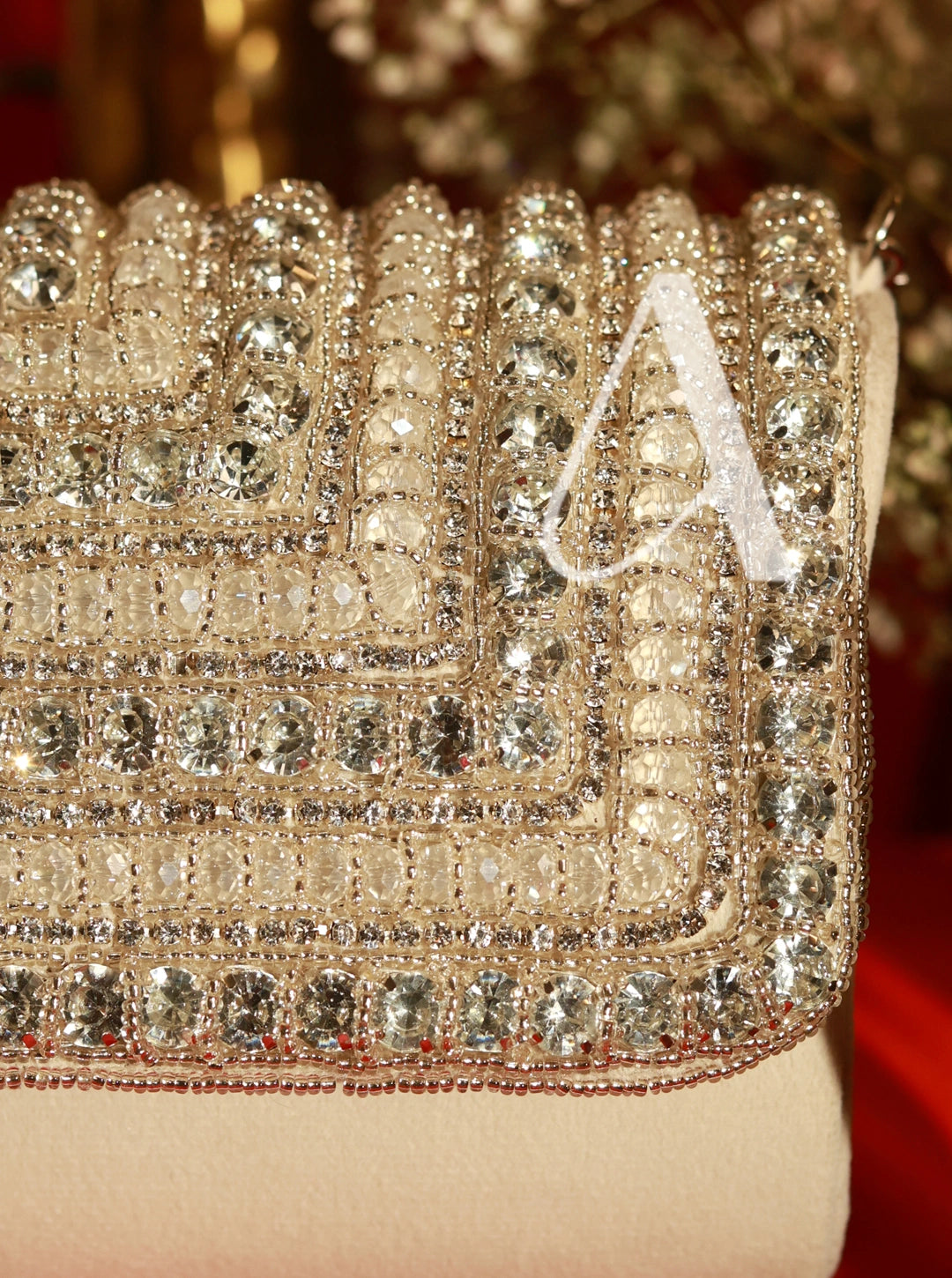 Close-up of a sparkling clutch with 'A' initials on a blurred background