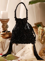 Black beaded handbag on a decorative surface with candles and flowers.