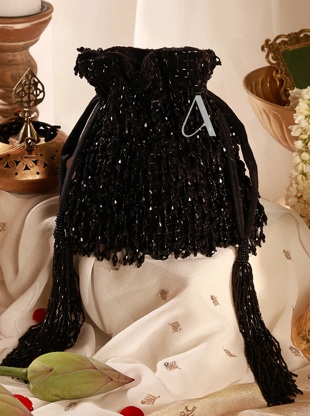Black beaded drawstring bag with tassels on a decorative surface