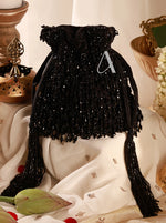 Black beaded drawstring bag with tassels on a decorative surface