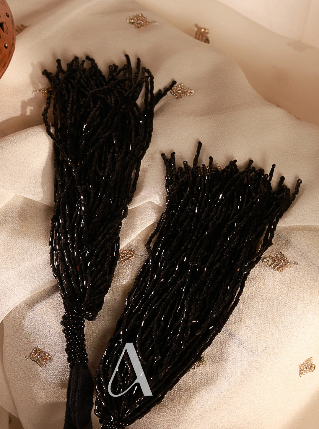 Black beaded hair accessories on a textured white surface