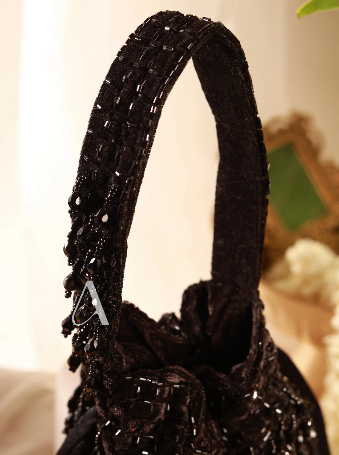Black beaded handbag with decorative elements on a blurred background