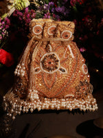 Decorative handbag with intricate designs and pearl embellishments on a dark background.