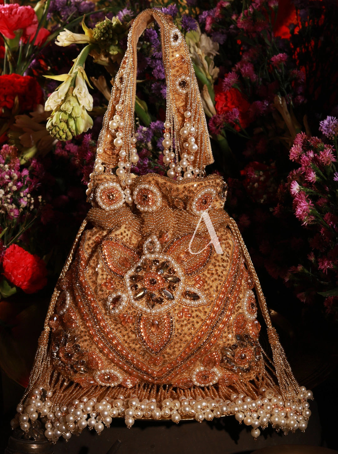 Decorative handbag with intricate beadwork in front of a floral background