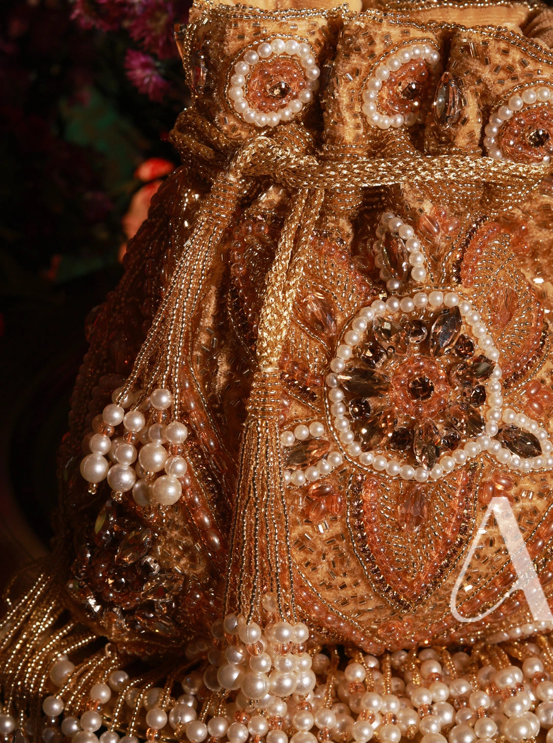 Decorative item with gold embroidery and pearls on a dark background