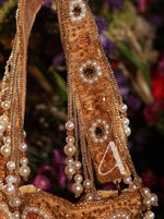 Decorative headband with pearls and gold embellishments against a blurred floral background