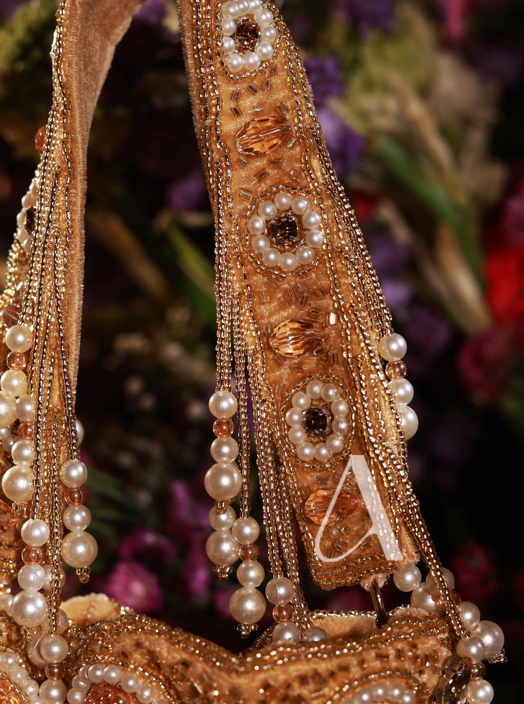 Decorative headband with pearls and gold embellishments against a blurred floral background