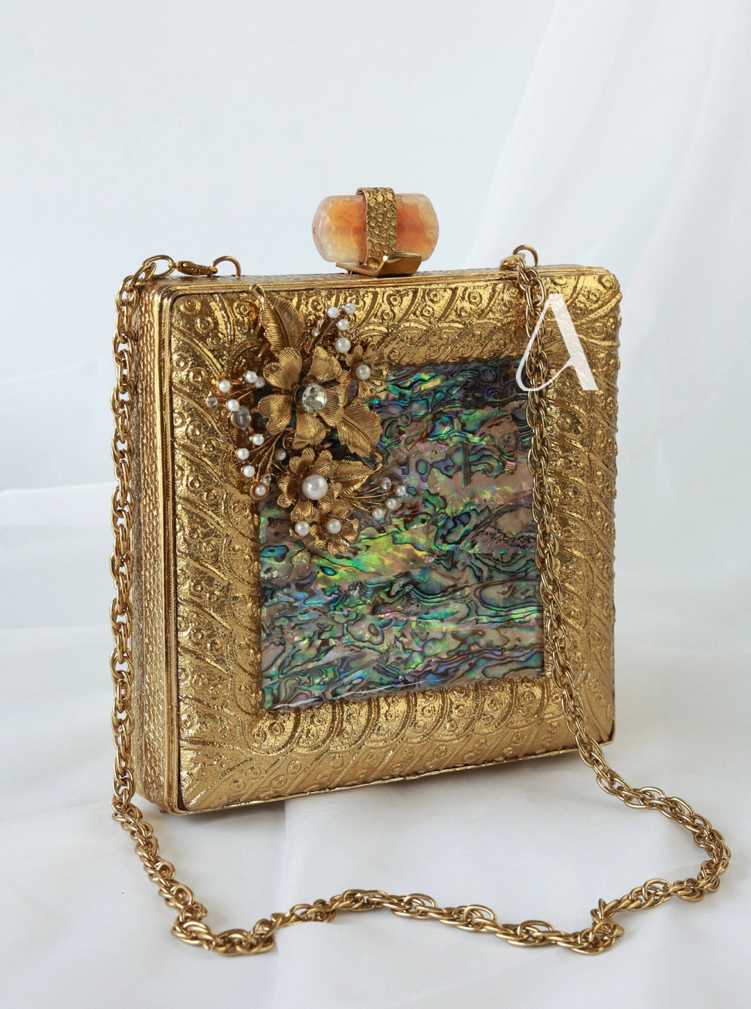 Gold clutch purse with floral embellishments on a white background