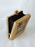 Gold clutch bag with decorative elements on a white background