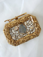 Gold clutch with gemstone embellishments on a white background
