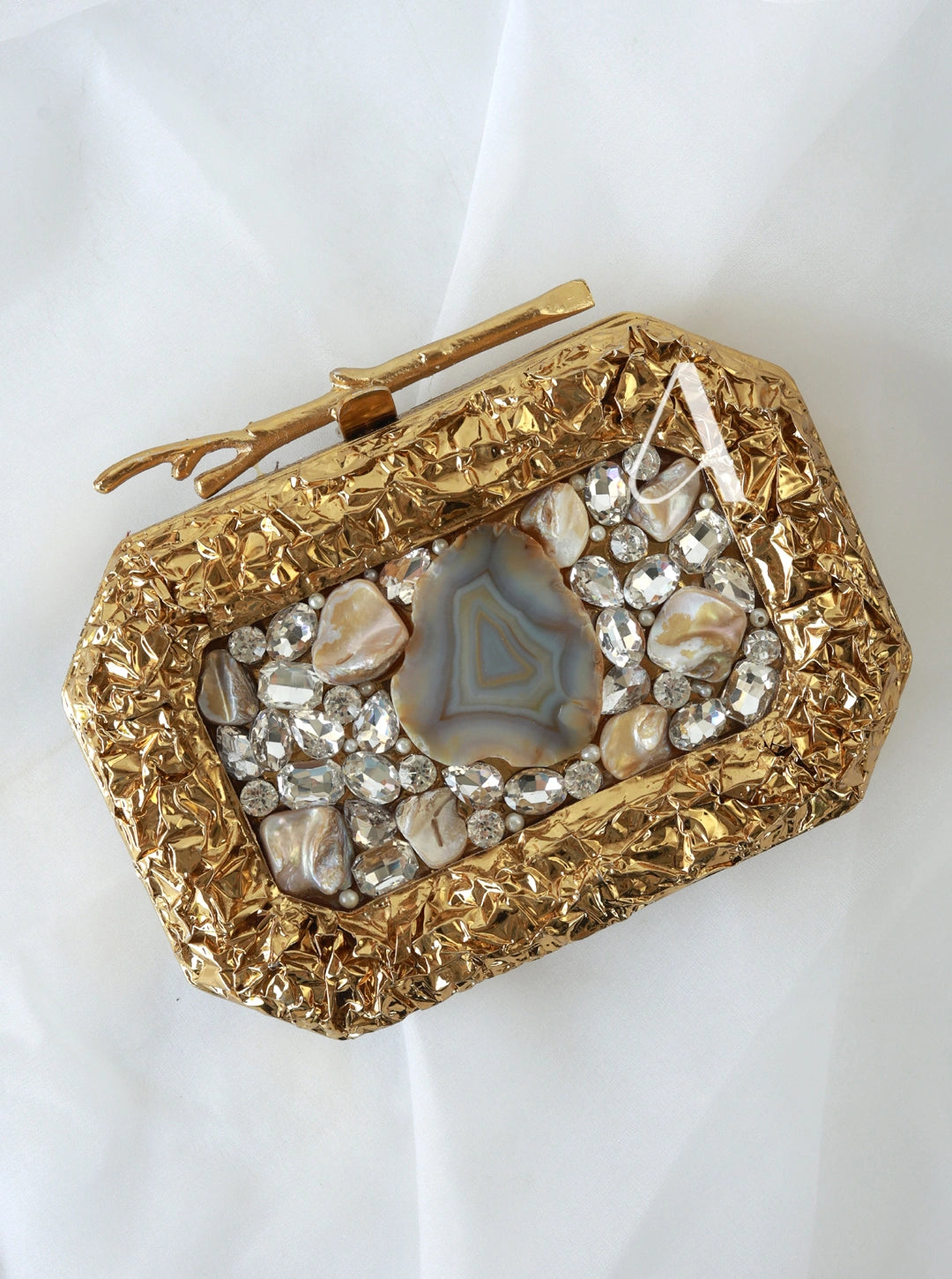 Gold clutch with gemstone embellishments on a white background
