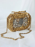 Gold clutch bag with decorative stones on a white background