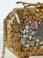 Gold clutch with gemstone accents on a white background