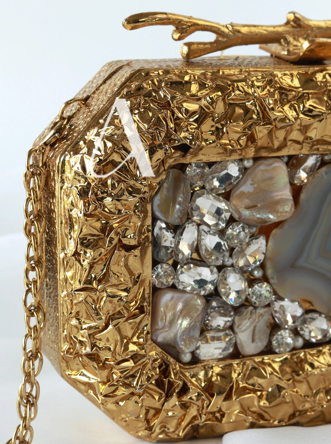 Gold clutch with gemstone accents on a white background