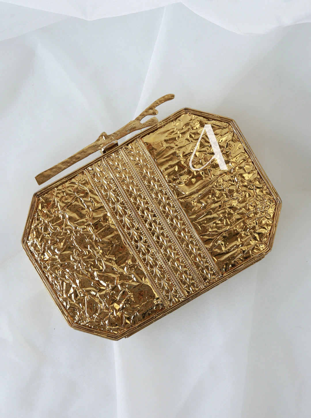 Gold clutch with intricate patterns on a white background