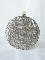 Decorative silver round object with intricate patterns on a white background