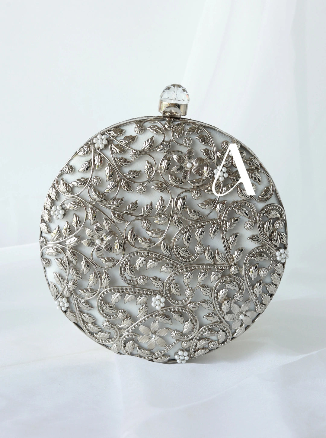 Decorative silver round object with intricate patterns on a white background