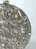 Close-up of a silver pendant with intricate floral patterns on a white background