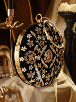 Black round clutch with gold floral embroidery on a decorative background