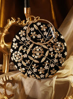 Decorative black clutch with gold floral embroidery on a gold and white fabric background
