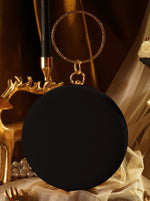 Black round object with a gold ring on a decorative background