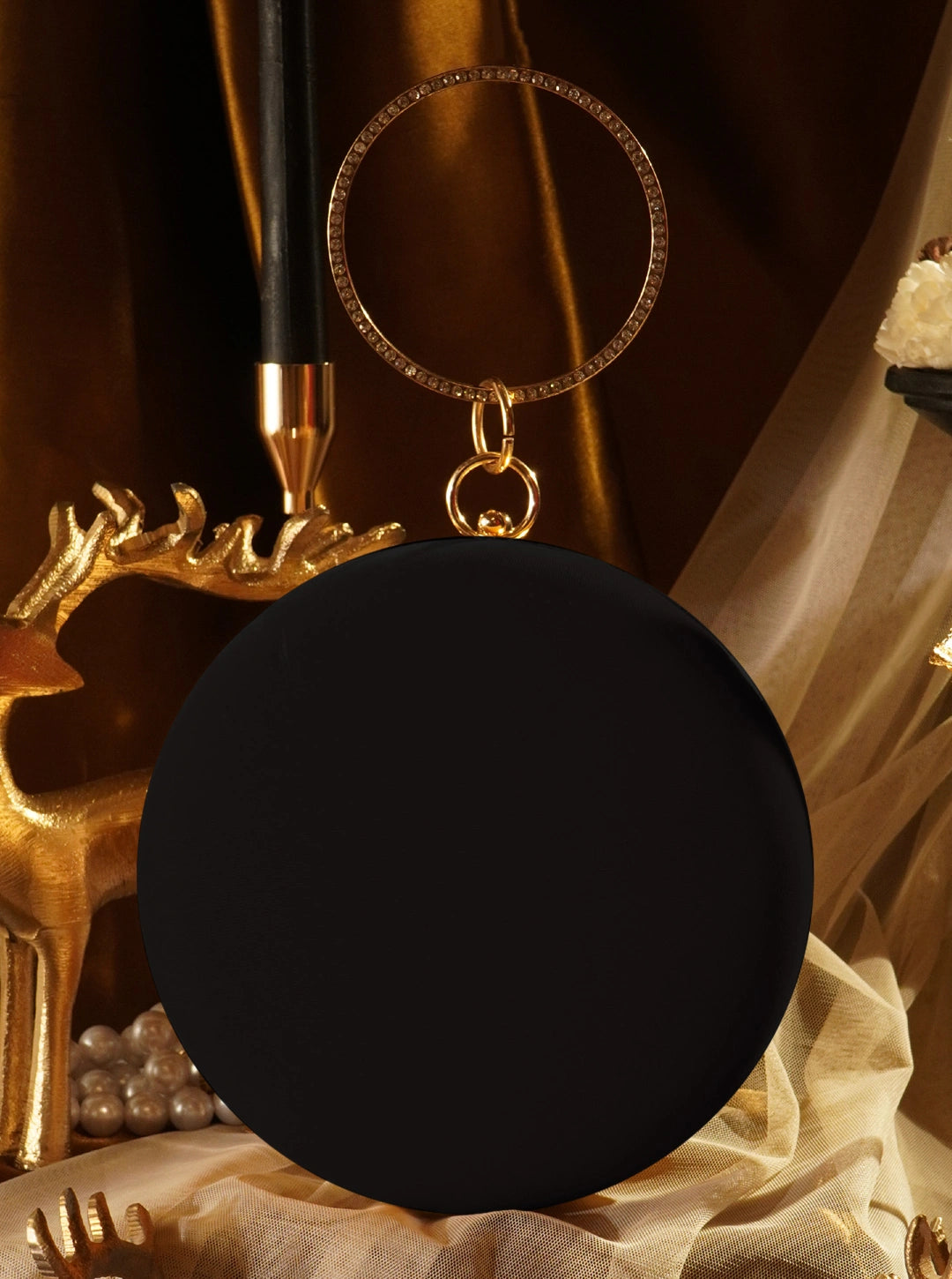 Black round object with a gold ring on a decorative background