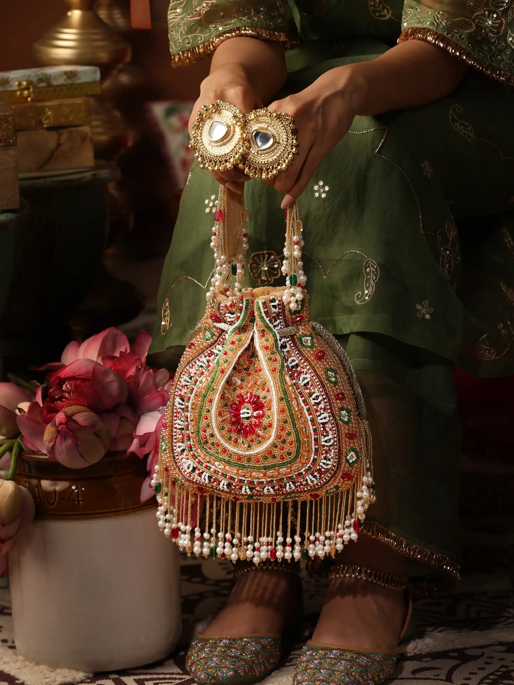 Decorative handbag with intricate designs held by a person in traditional attire.