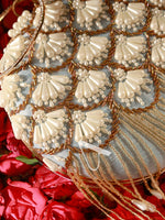 Decorative clutch with pearl and gold detailing on a red floral background