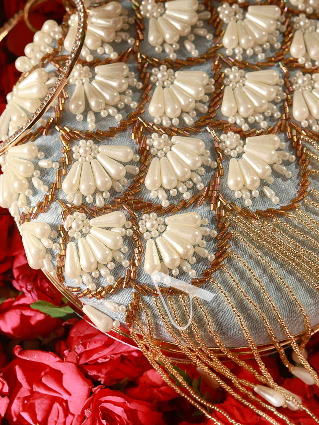Decorative clutch with pearl and gold detailing on a red floral background