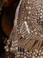 Decorative item with pearls and a letter 'A' on a dark background