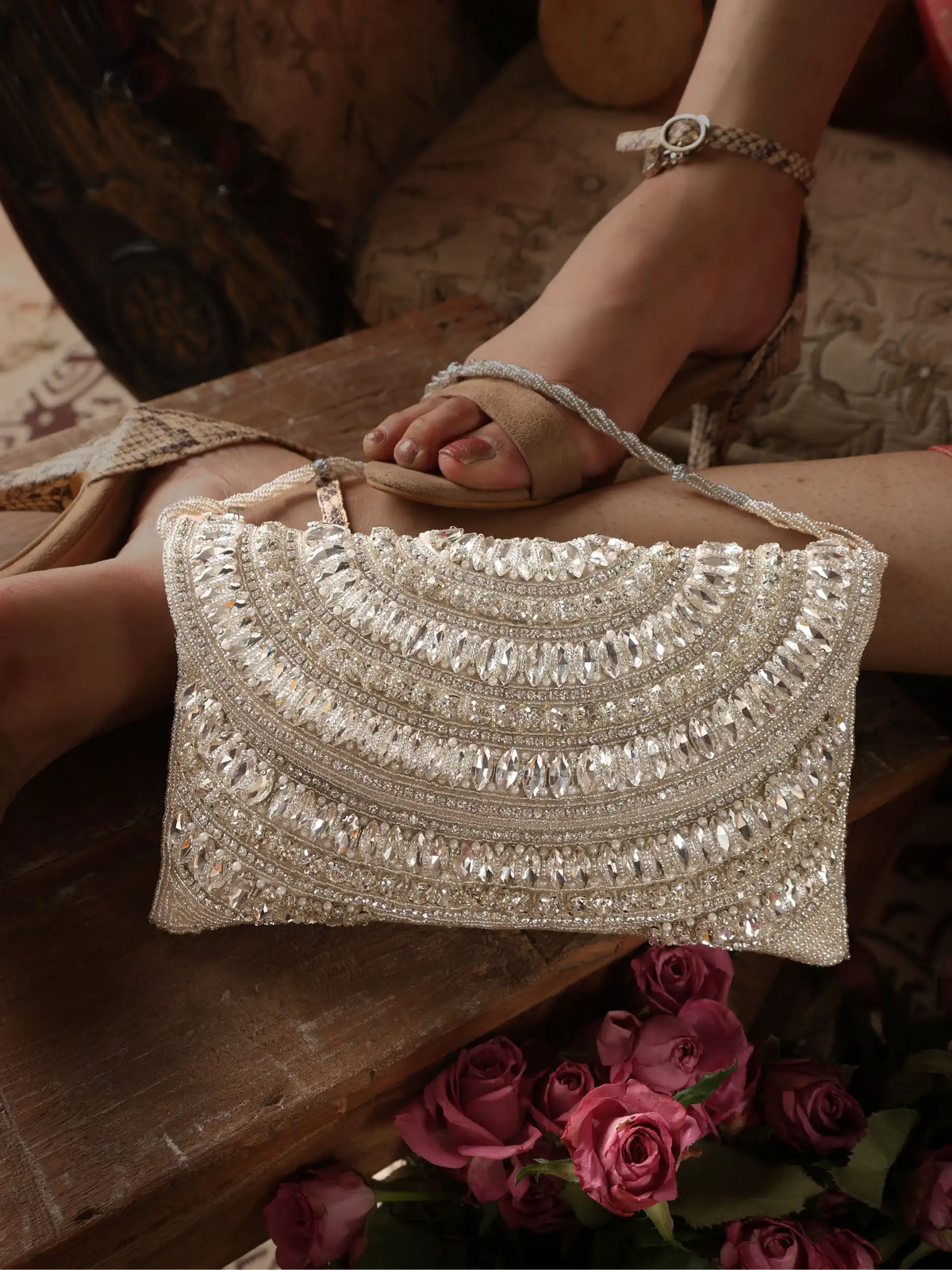Silver beaded handbag held by a foot with a floral background
