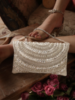 Silver beaded handbag held by a foot with a floral background