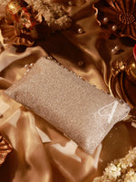 Sparkly clutch bag on a textured fabric background with decorative elements