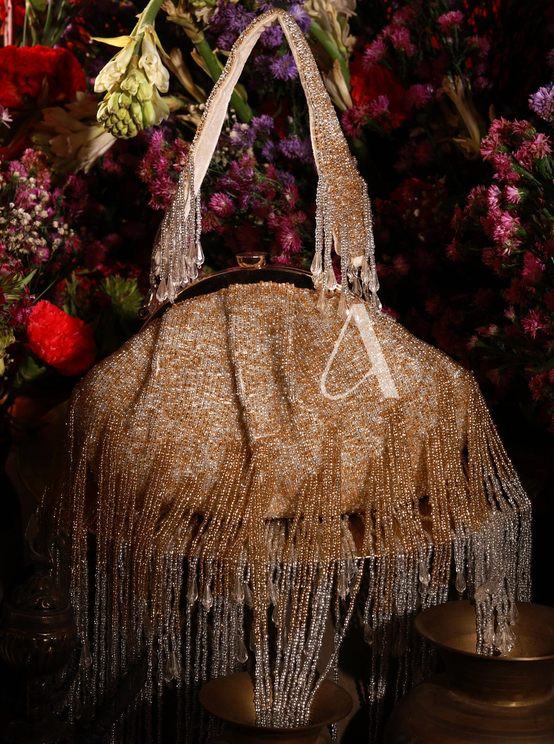 Beaded handbag with fringe detail in front of a floral background