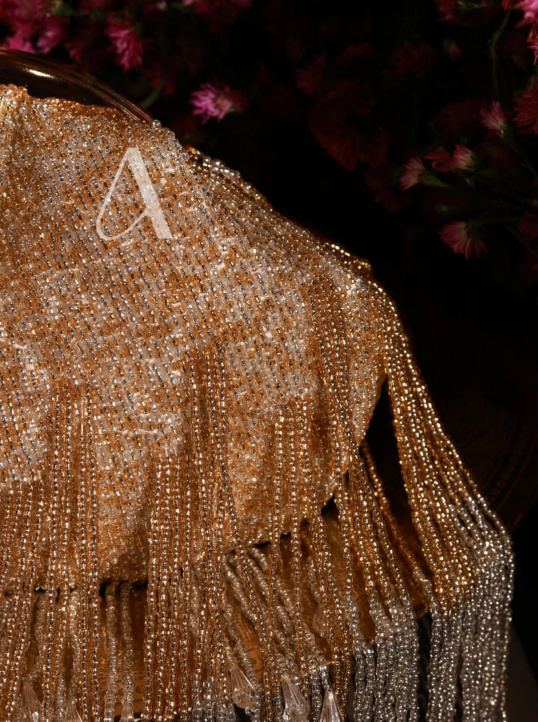 Close-up of a beaded fabric with a letter 'A' on a dark background