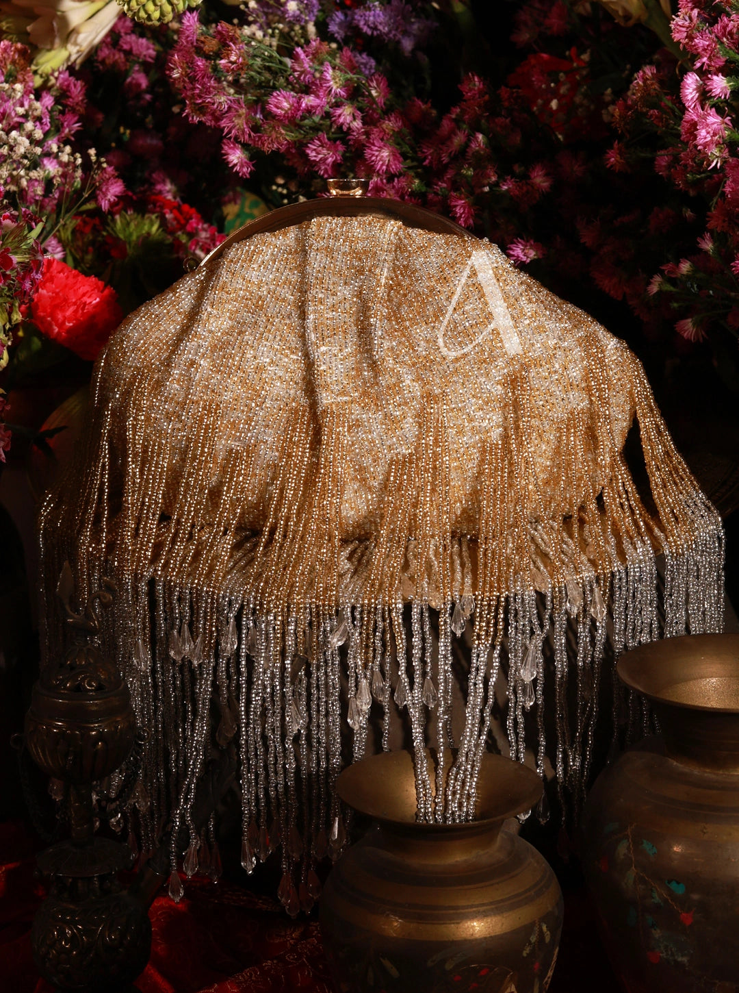 Decorative lampshade with fringe and beads on a dark background with flowers.