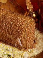 Gold beaded bag with decorative elements on a floral background