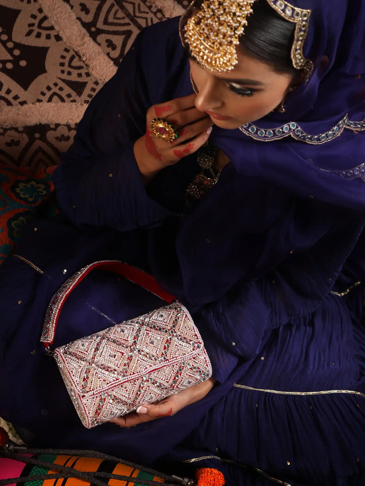Woman in traditional attire holding a patterned handbag with a decorative background