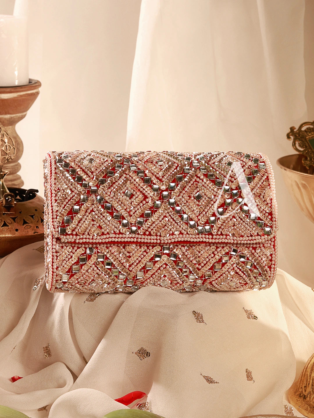 Decorative clutch bag with intricate beadwork on a draped fabric background