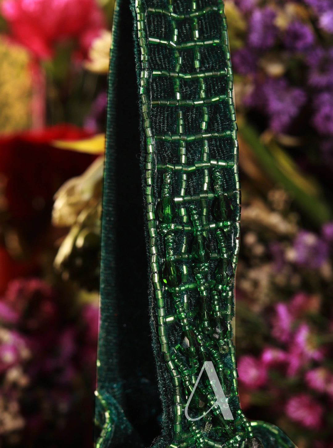 Close-up of a green beaded strap with a blurred floral background